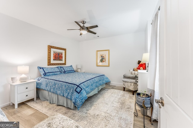 bedroom with ceiling fan, light wood-style flooring, and baseboards