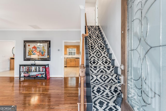 foyer with sink, ornamental molding, and hardwood / wood-style floors