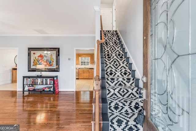 interior space featuring baseboards, wood finished floors, and crown molding