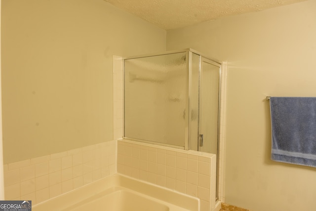 bathroom featuring independent shower and bath and a textured ceiling