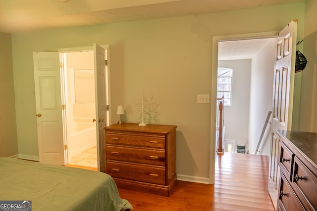 bedroom featuring ensuite bath and light hardwood / wood-style flooring