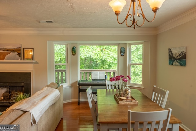 dining room with crown molding, hardwood / wood-style floors, a textured ceiling, and an inviting chandelier