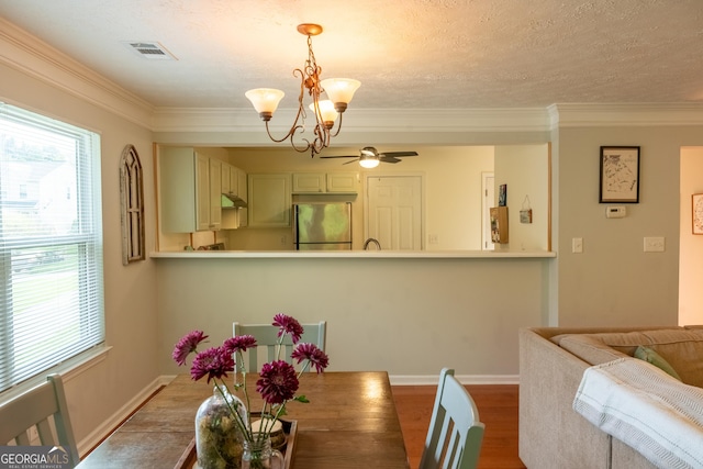 dining space with hardwood / wood-style flooring, ornamental molding, a healthy amount of sunlight, and ceiling fan with notable chandelier