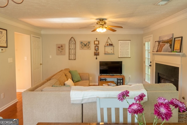 living room featuring hardwood / wood-style flooring, ornamental molding, a textured ceiling, and ceiling fan