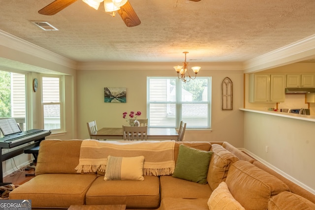 living room featuring ceiling fan with notable chandelier, ornamental molding, and a textured ceiling