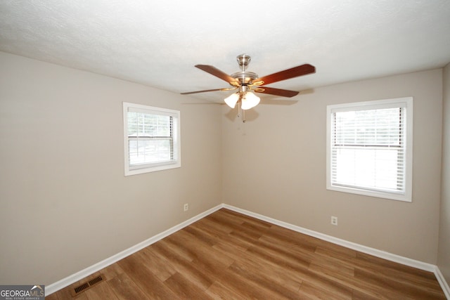 unfurnished room with a textured ceiling, plenty of natural light, ceiling fan, and hardwood / wood-style flooring