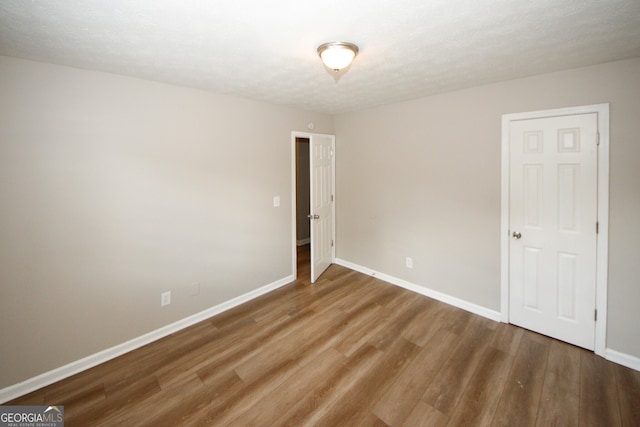 empty room featuring wood-type flooring and a textured ceiling