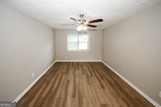 empty room featuring a textured ceiling, dark wood-type flooring, and ceiling fan