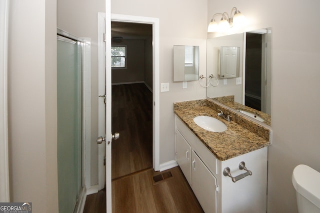 bathroom with hardwood / wood-style floors, vanity, toilet, and a shower with door