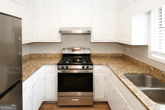 kitchen with light stone countertops, white cabinets, appliances with stainless steel finishes, and ventilation hood