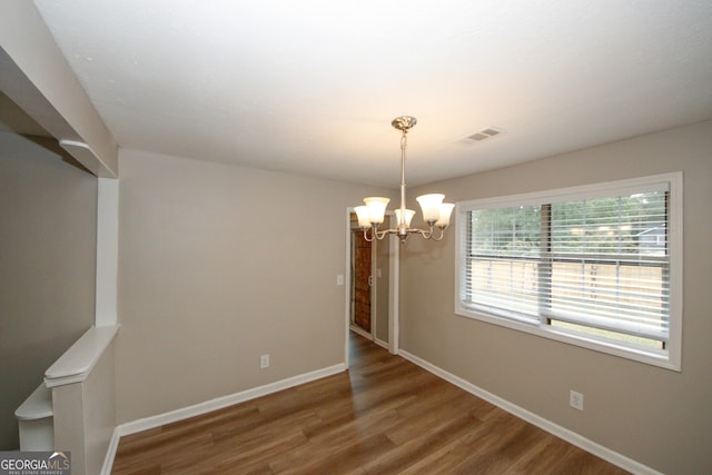 spare room featuring a notable chandelier and hardwood / wood-style flooring