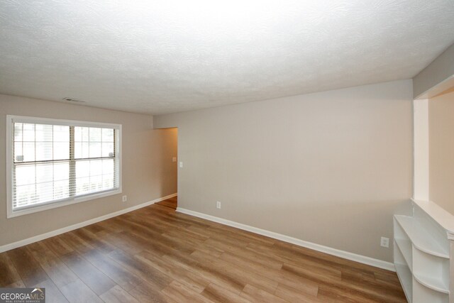 unfurnished room featuring a textured ceiling and hardwood / wood-style flooring