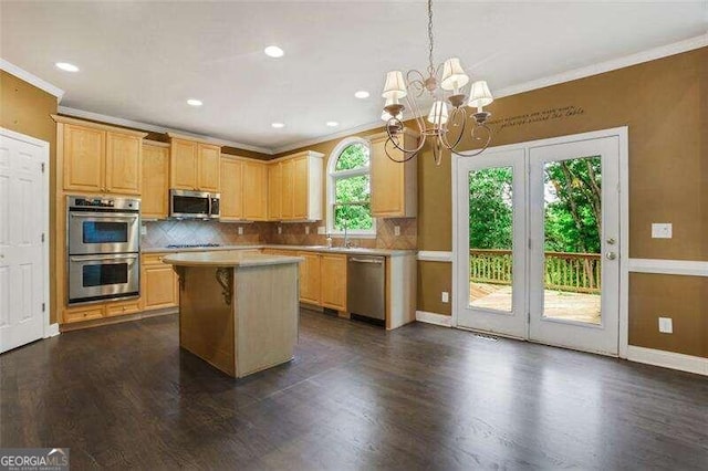 kitchen featuring dark wood-type flooring, ornamental molding, appliances with stainless steel finishes, backsplash, and a center island