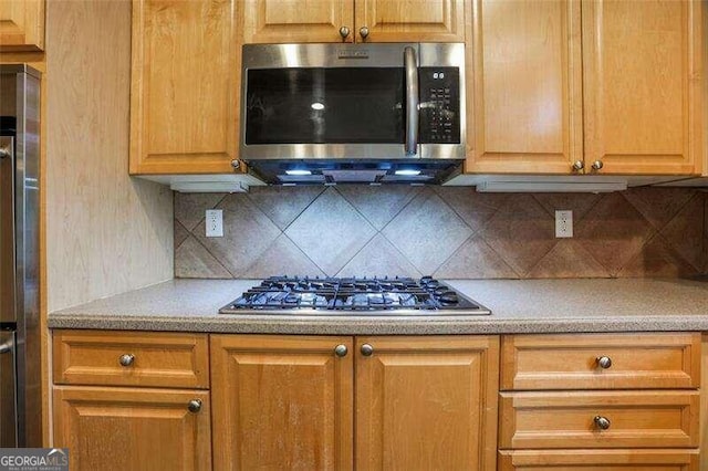 kitchen featuring stainless steel appliances, light countertops, and backsplash