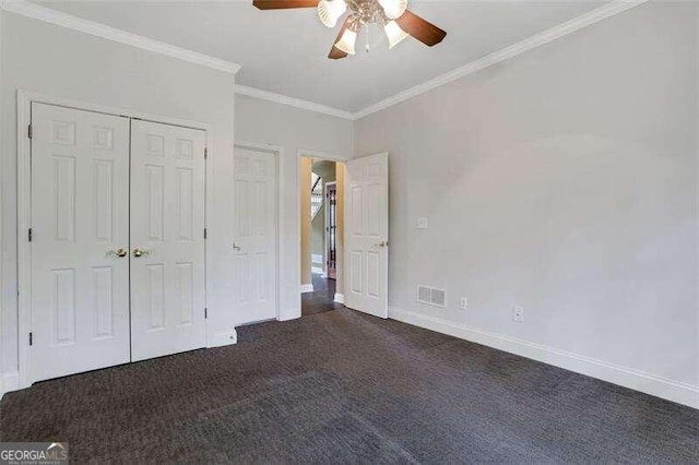 unfurnished bedroom featuring baseboards, visible vents, crown molding, dark carpet, and a closet