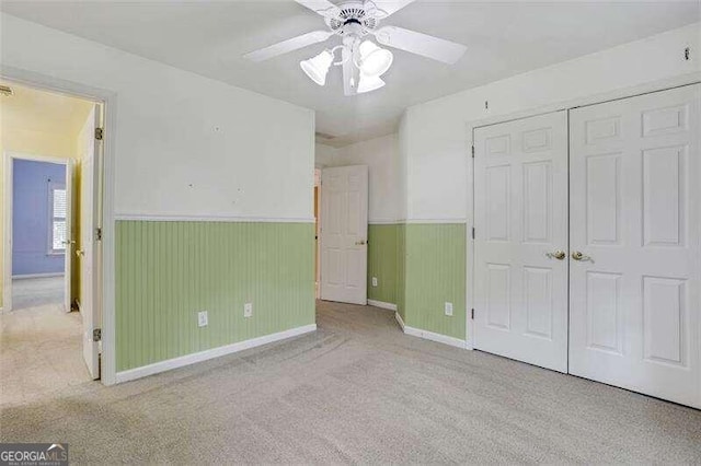 unfurnished bedroom with ceiling fan, a closet, carpet flooring, and wainscoting