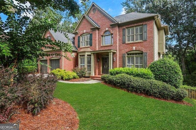 view of front of home featuring an attached garage, brick siding, and a front yard