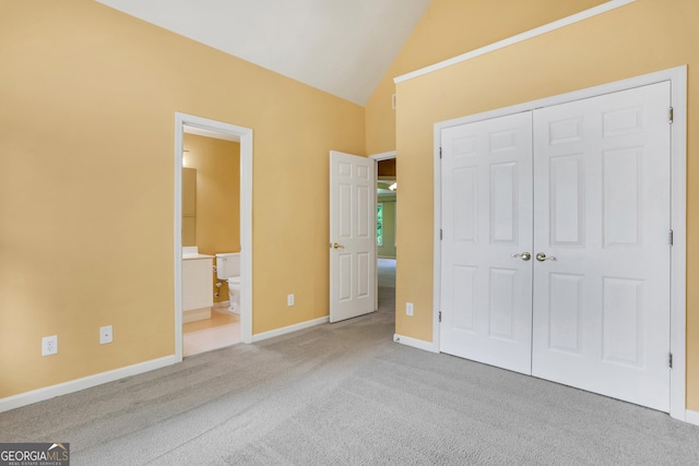 unfurnished bedroom featuring baseboards, lofted ceiling, ensuite bathroom, carpet, and a closet