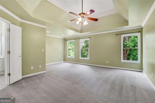 carpeted empty room with ornamental molding, a raised ceiling, baseboards, and a ceiling fan