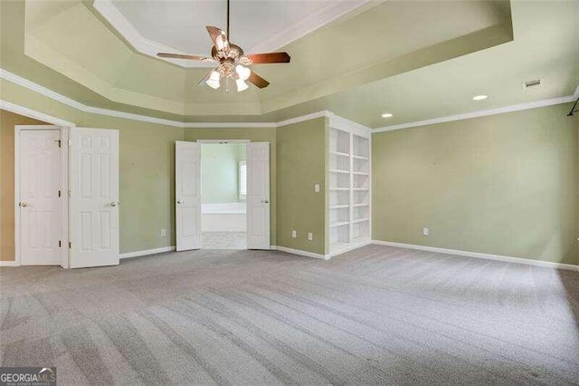 unfurnished bedroom with baseboards, carpet, a tray ceiling, and crown molding