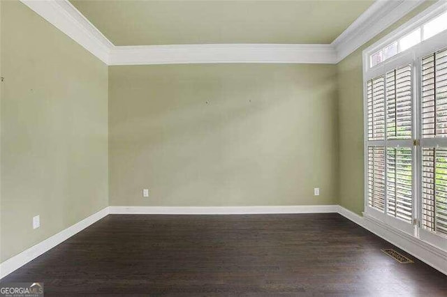 empty room featuring baseboards, dark wood finished floors, and crown molding