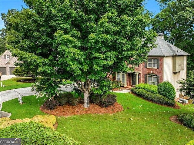 view of front of home with brick siding, a chimney, and a front yard