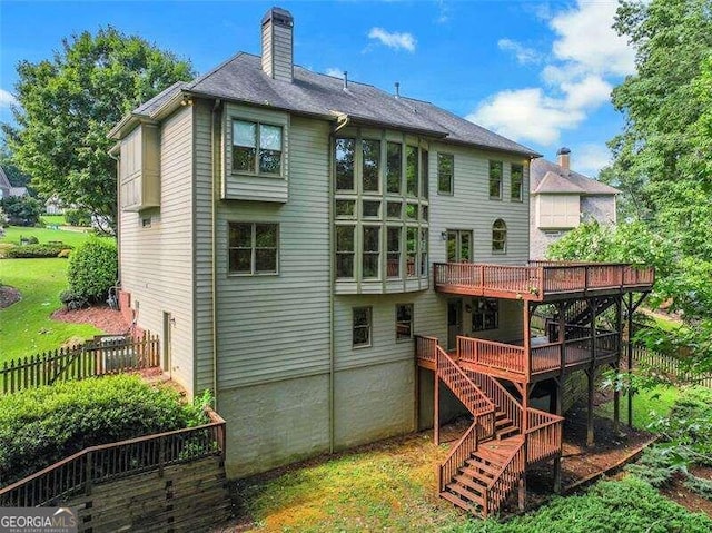 rear view of property featuring stairs, a deck, a chimney, and fence