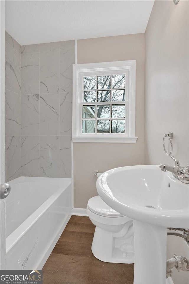 bathroom featuring tiled shower / bath, hardwood / wood-style floors, and toilet