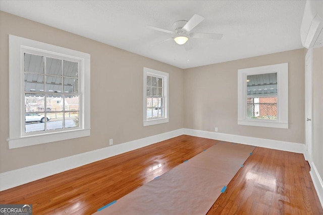 empty room with a healthy amount of sunlight, hardwood / wood-style floors, and a wall unit AC