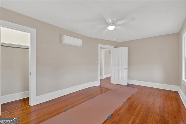 unfurnished bedroom with ceiling fan, wood-type flooring, a wall mounted AC, and a closet