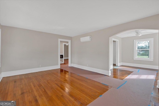 unfurnished room with hardwood / wood-style flooring, ceiling fan, and a wall mounted AC