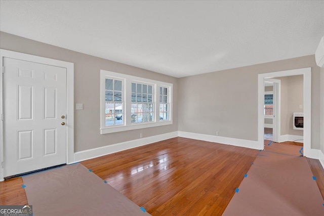 unfurnished living room featuring heating unit and hardwood / wood-style flooring