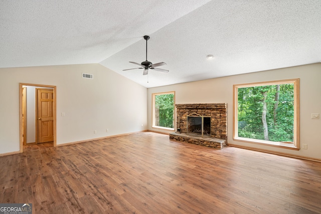 unfurnished living room with a fireplace, vaulted ceiling, wood-type flooring, ceiling fan, and a textured ceiling