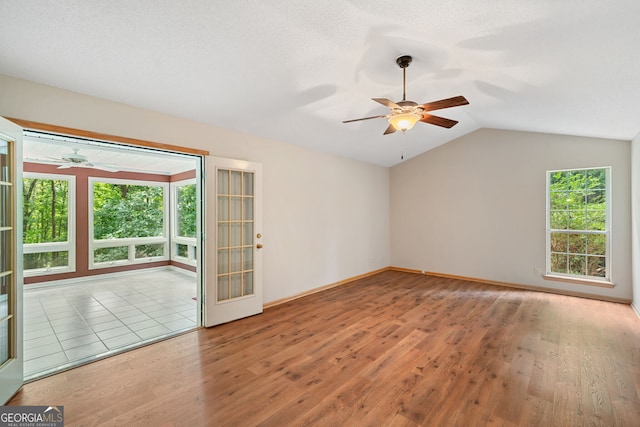 empty room featuring lofted ceiling, light hardwood / wood-style flooring, ceiling fan, and a textured ceiling