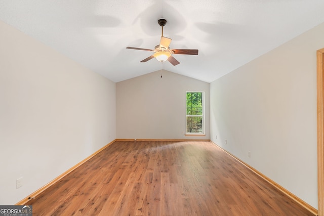 empty room with ceiling fan, hardwood / wood-style floors, and vaulted ceiling