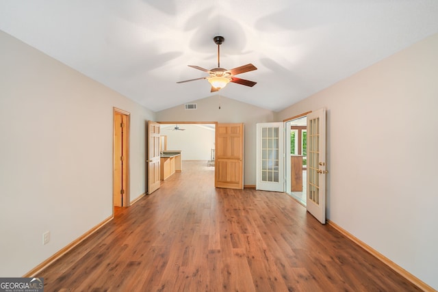 empty room featuring french doors, ceiling fan, hardwood / wood-style floors, and vaulted ceiling