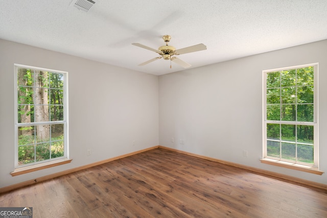 spare room featuring a wealth of natural light, ceiling fan, hardwood / wood-style floors, and a textured ceiling