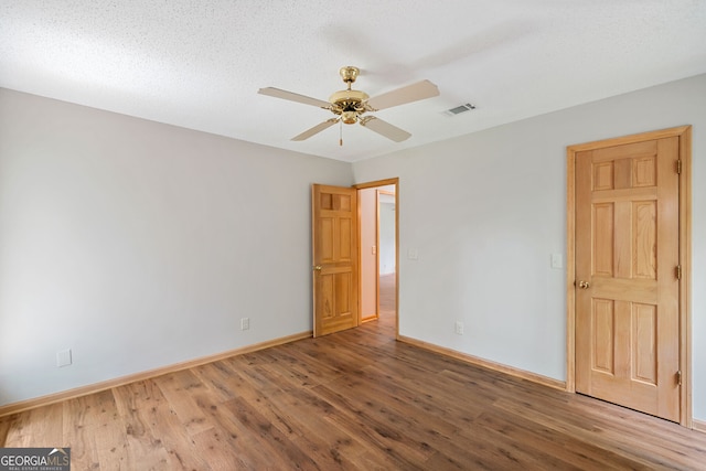 empty room featuring ceiling fan, wood-type flooring, and a textured ceiling