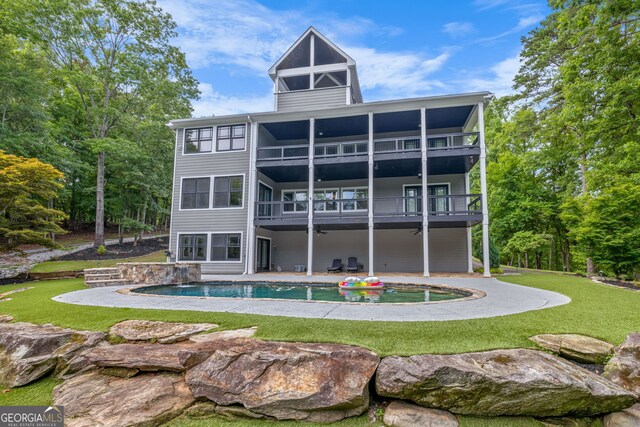 back of property featuring a balcony, a lawn, and a patio area