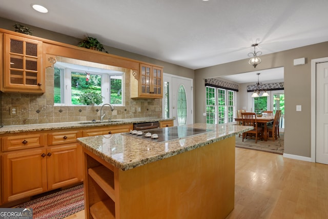 kitchen featuring hanging light fixtures, a center island, light stone counters, and light wood-type flooring