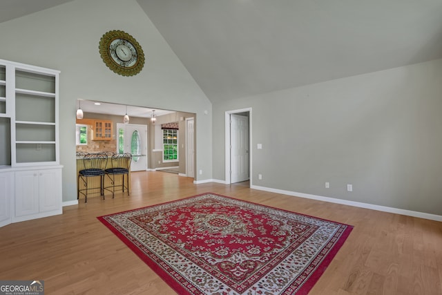 living room featuring light hardwood / wood-style floors, built in features, and high vaulted ceiling