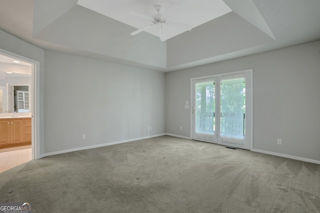 empty room featuring carpet flooring, a tray ceiling, sink, and ceiling fan