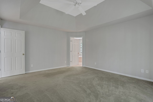 carpeted spare room featuring a raised ceiling and ceiling fan