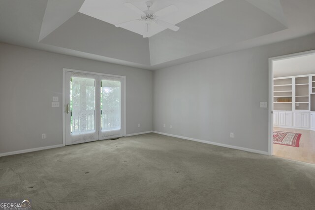 carpeted spare room with ceiling fan and a tray ceiling