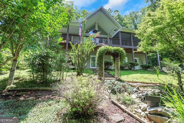 back of property with a balcony and a yard