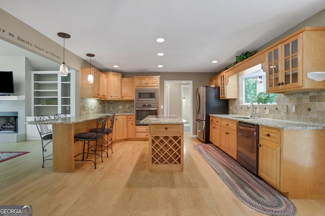 kitchen featuring a fireplace, sink, appliances with stainless steel finishes, and light wood-type flooring