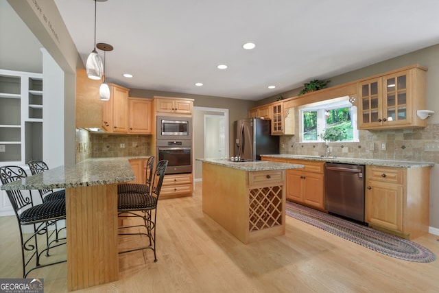 kitchen with appliances with stainless steel finishes, light hardwood / wood-style flooring, decorative backsplash, and light stone counters