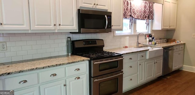 kitchen featuring white cabinets, stainless steel appliances, dark hardwood / wood-style floors, and decorative backsplash