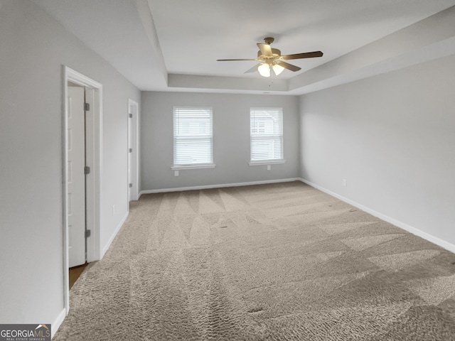 carpeted empty room featuring ceiling fan and a tray ceiling