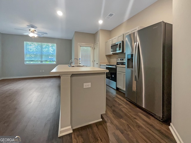 kitchen with sink, appliances with stainless steel finishes, an island with sink, white cabinets, and dark hardwood / wood-style flooring